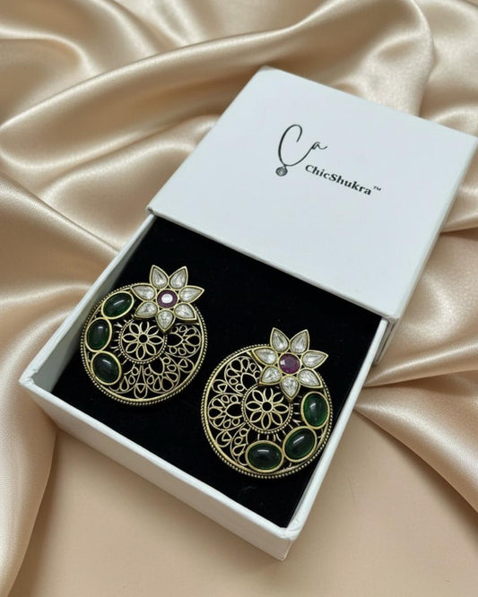 ChicShukra brass filigree earrings with green and ruby stones in a white jewellery box on satin fabric