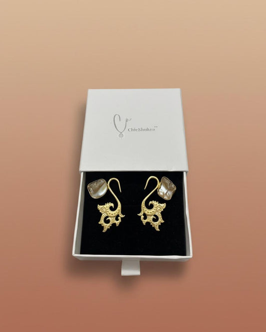 Chicshukra gold‑tone peacock earrings with transparent crystal stones displayed on a black stand, styled as imitation bracelet jewellery.