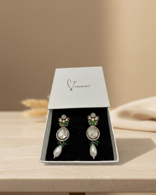 Pair of earrings in a Chloebella box on a wooden surface with a beige background