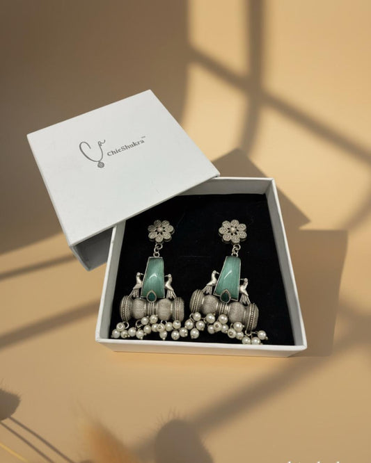 Earrings in a white box with 'ChicNooka' branding on a beige background