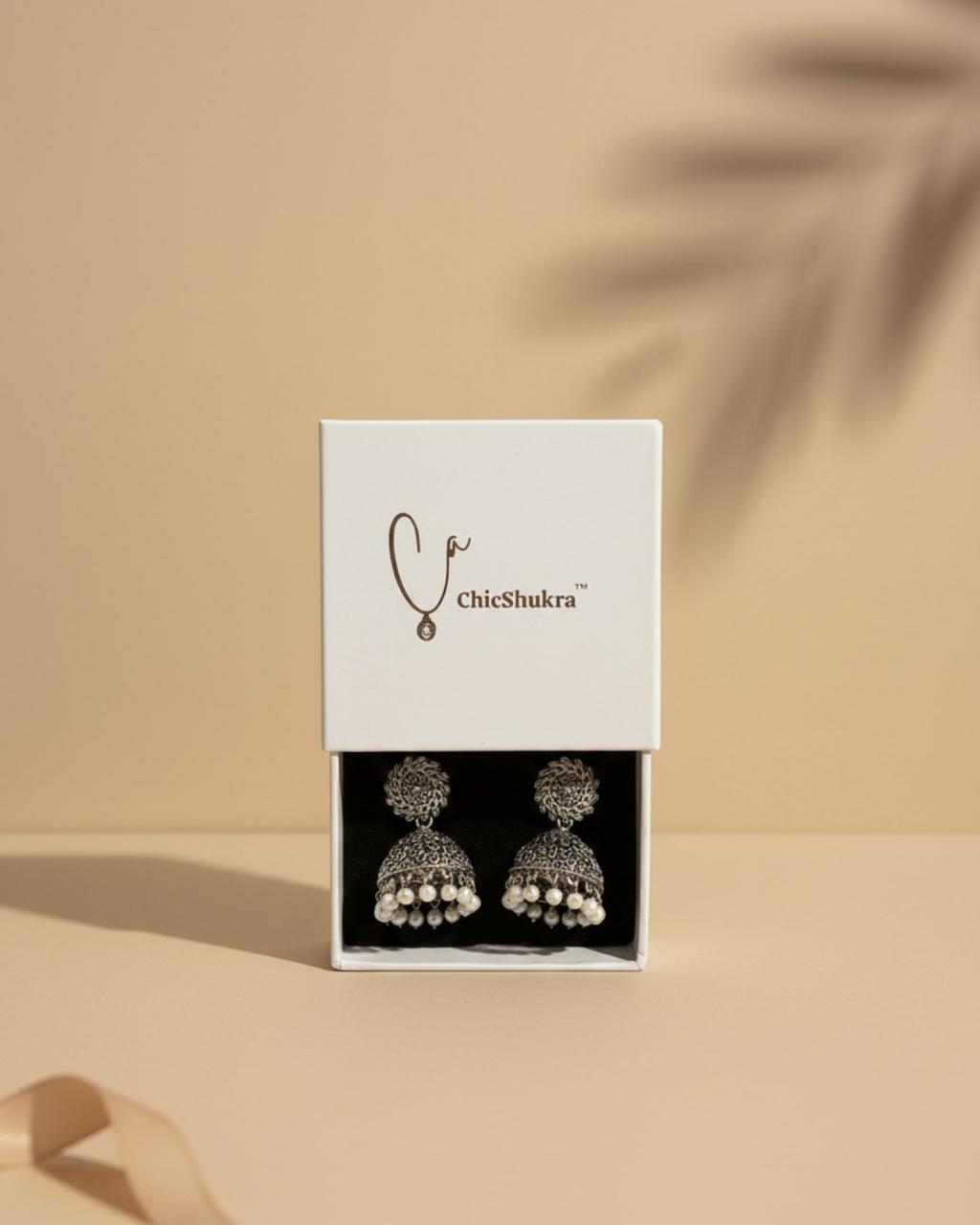ChicShukra earrings in a white box on a beige background