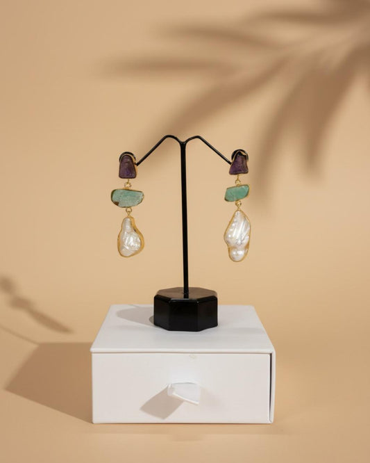 Pair of earrings on a black stand with a beige background
