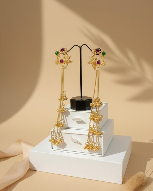 Gold earrings with gemstones on a white stand against beige background