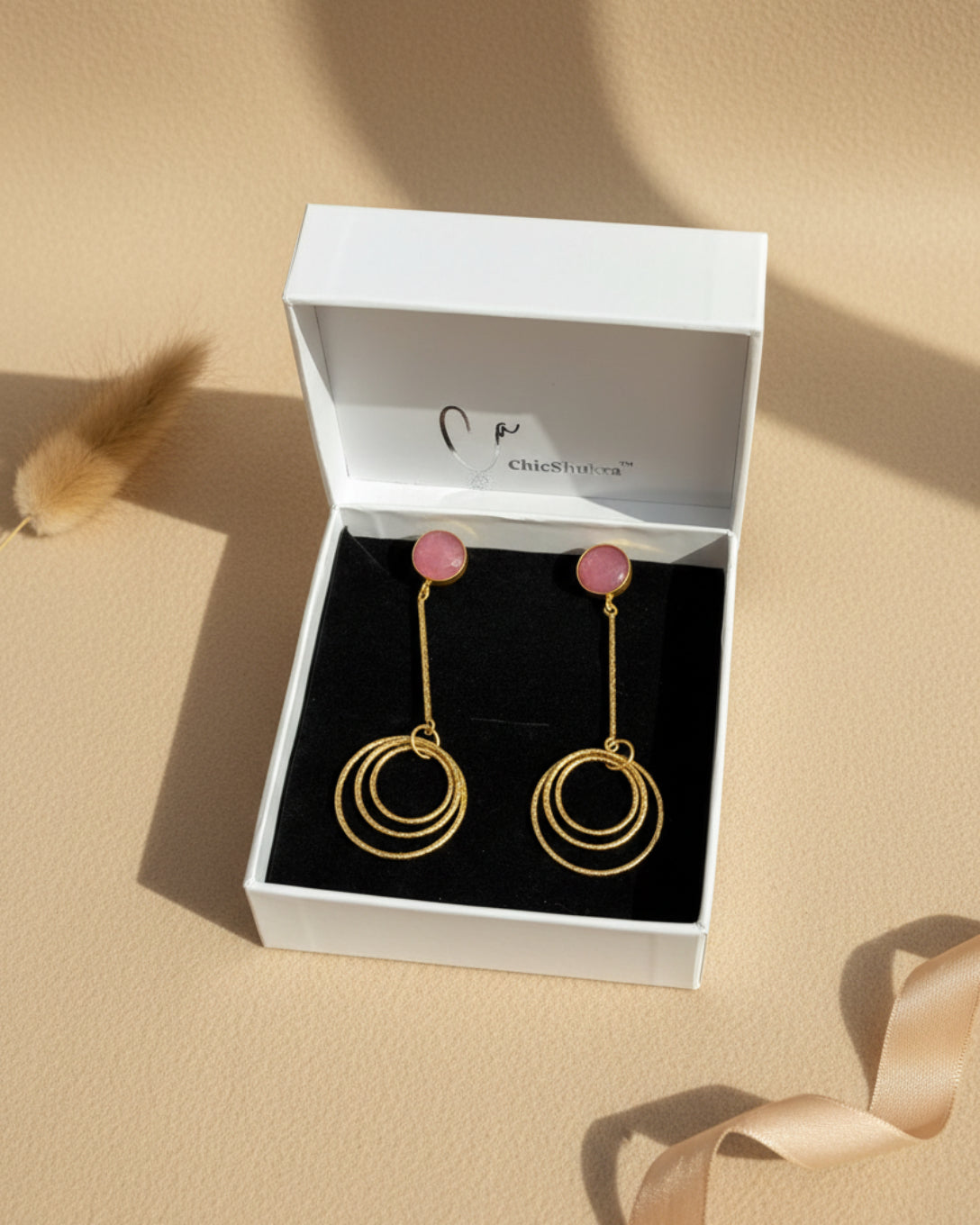 Gold hoop earrings with pink stones in a ChicShukra box.
