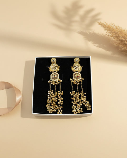 Statement Kashmiri jhumkas with hexagonal neutral stones, floral kundan motifs, and dramatic gold-tone bell tassel strands.
