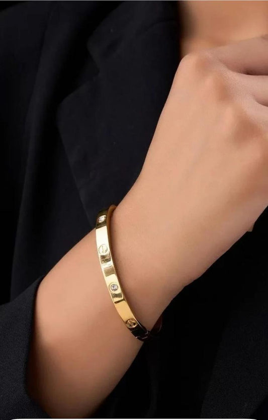 Gold bracelet on a wrist with a dark background