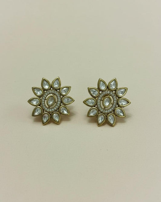 Pair of gold floral earrings with gemstones on a beige background