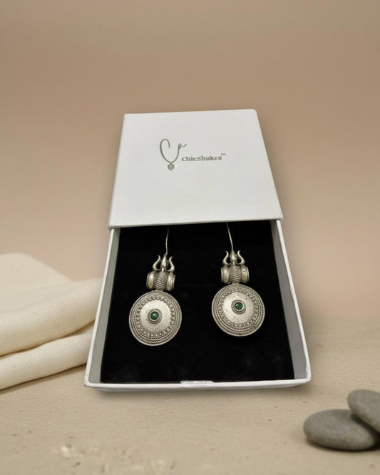 Silver earrings with green gemstones in a Chichikaka box on a beige background