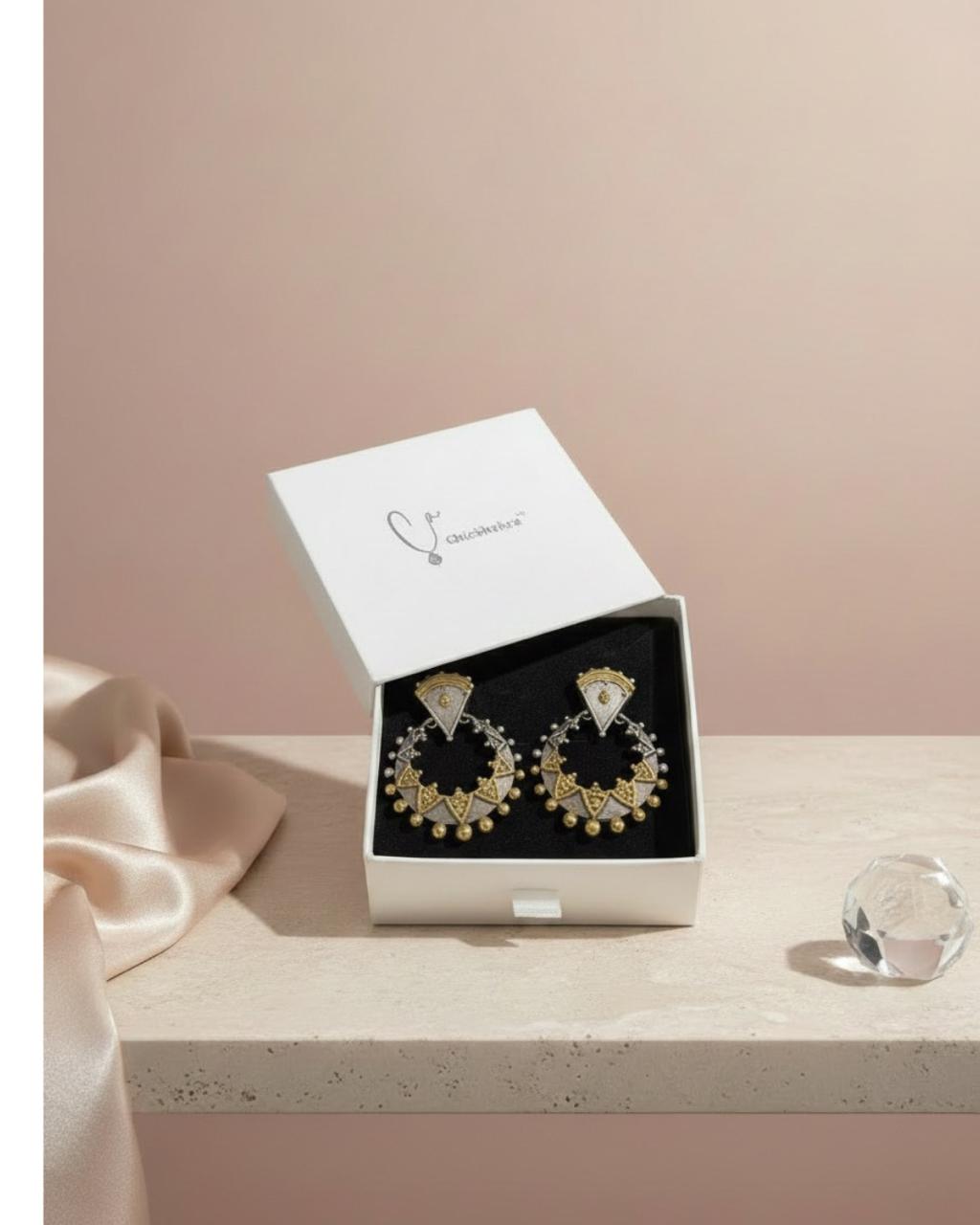 Gold hoop earrings in a white box on a light pink background