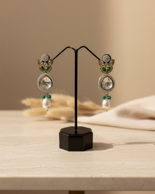 ChicShukra imitation jewellery earrings with polki stones, emerald green accents, and pearl drops displayed on a black stand.