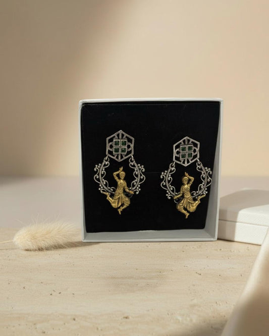 Pair of gold and silver earrings on a black display card with a beige background