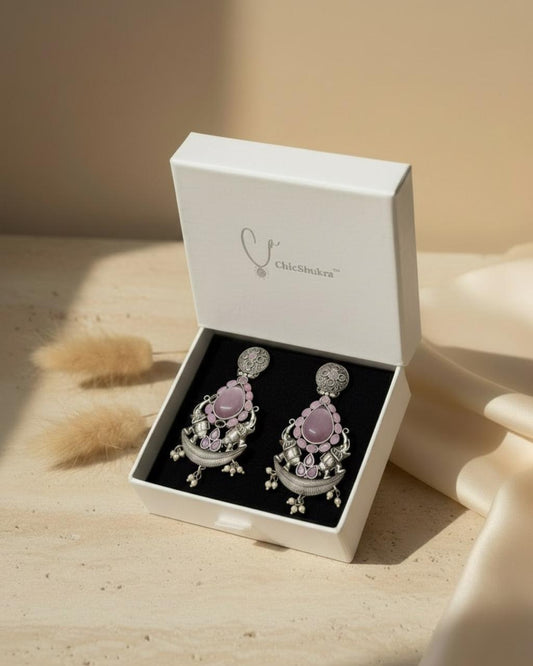 Pair of earrings in a white box on a wooden surface
