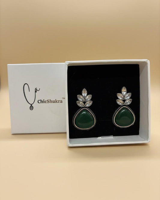 ChicShukra brass earrings with green teardrop stones and silver crystal flower tops in a white box