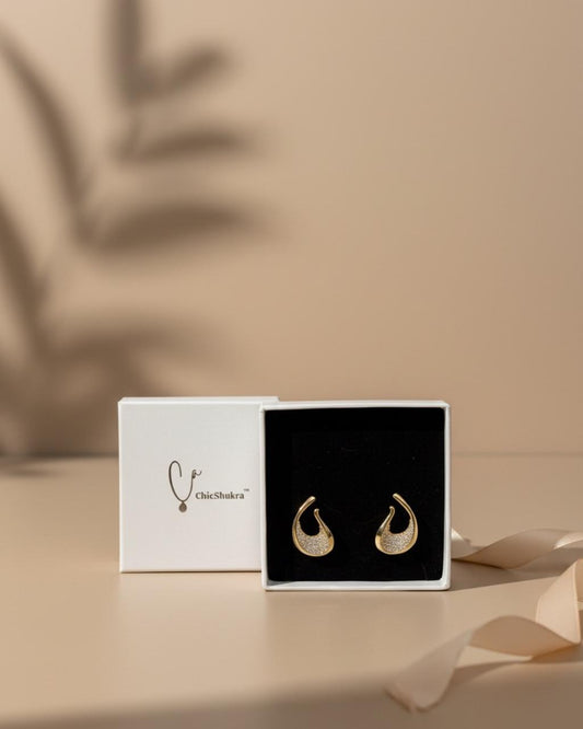 ChicShukra gold‑finish brass teardrop earrings with zirconia accents in a white branded box with black velvet insert
