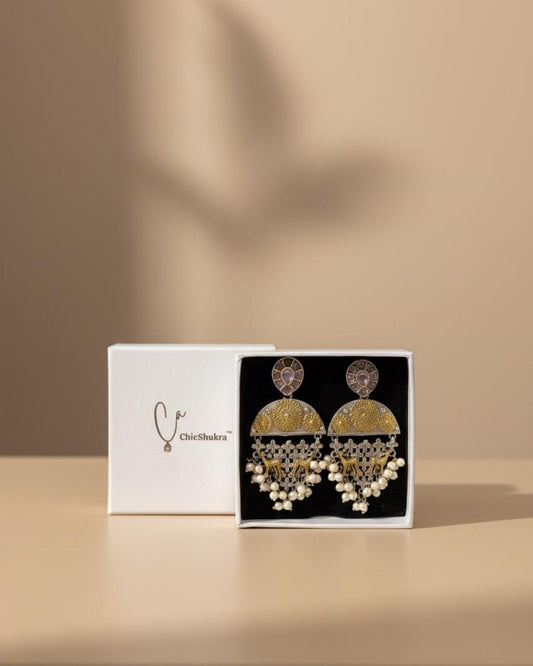 Gold earrings in a box with a beige background