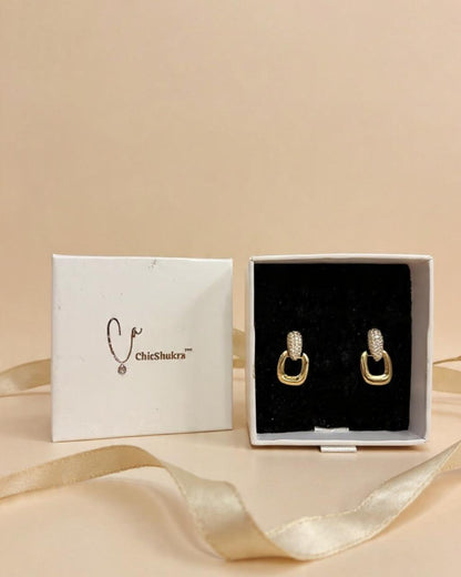 Gold hoop earrings in a white box with 'ChicShukra' branding on a beige background.