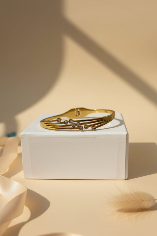 Gold bracelet on a white box with a beige background