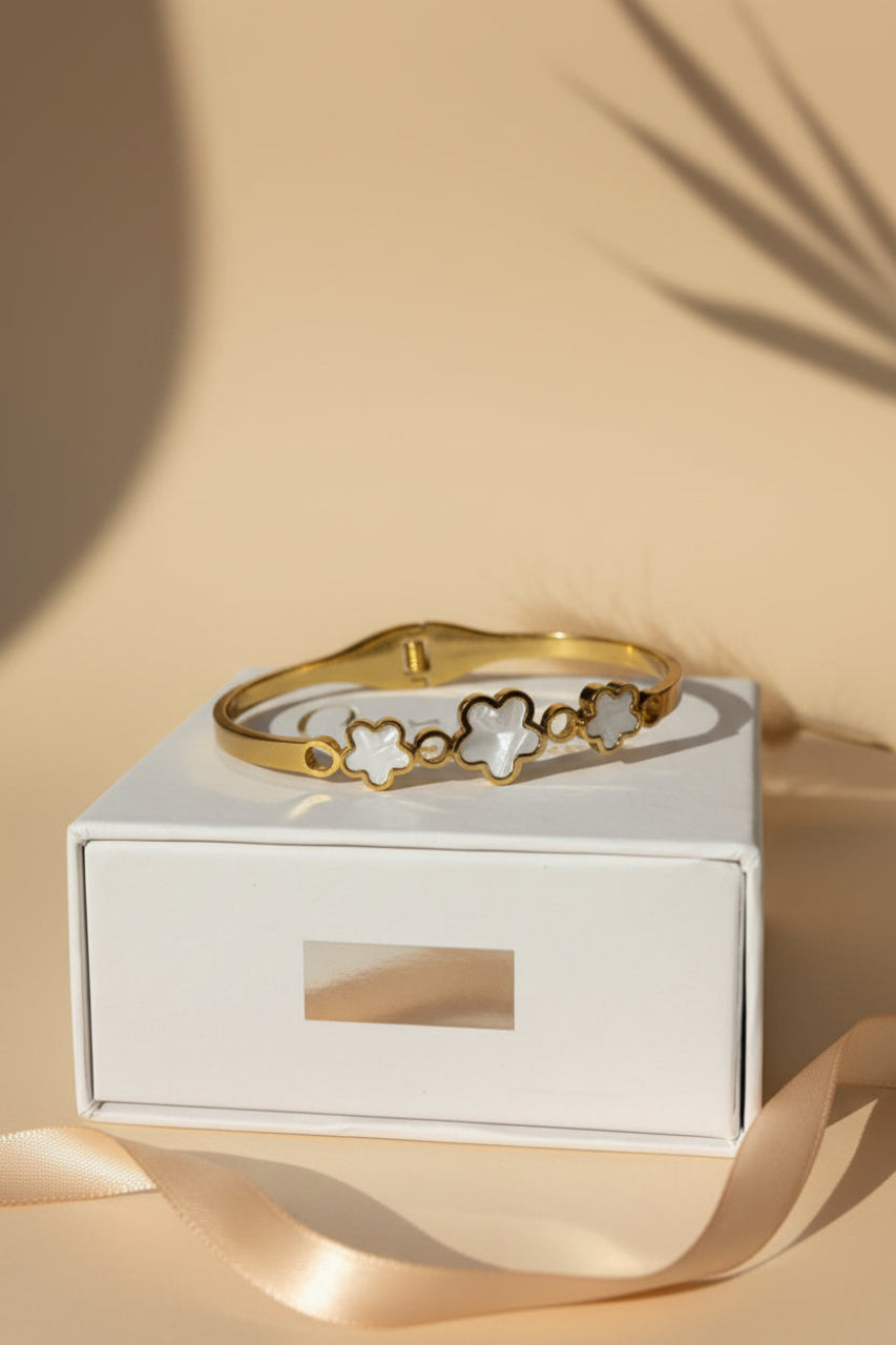 Gold bracelet on a white box with a beige background