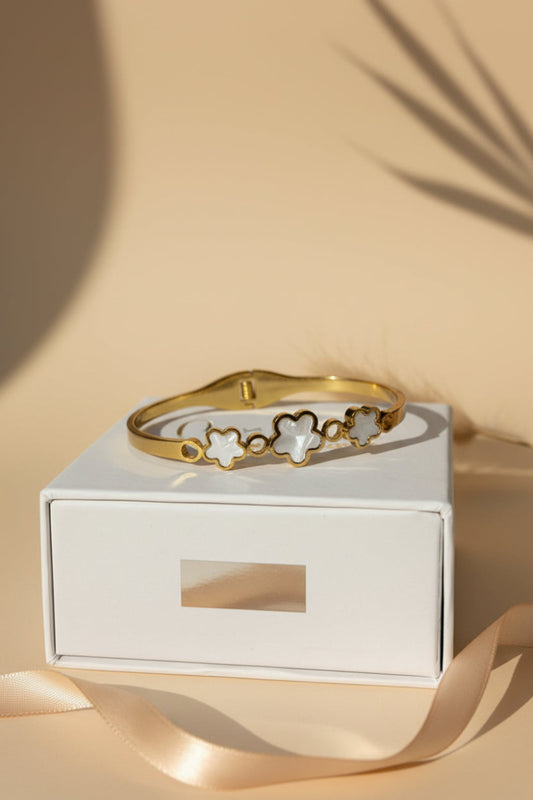 Gold bracelet on a white box with a beige background