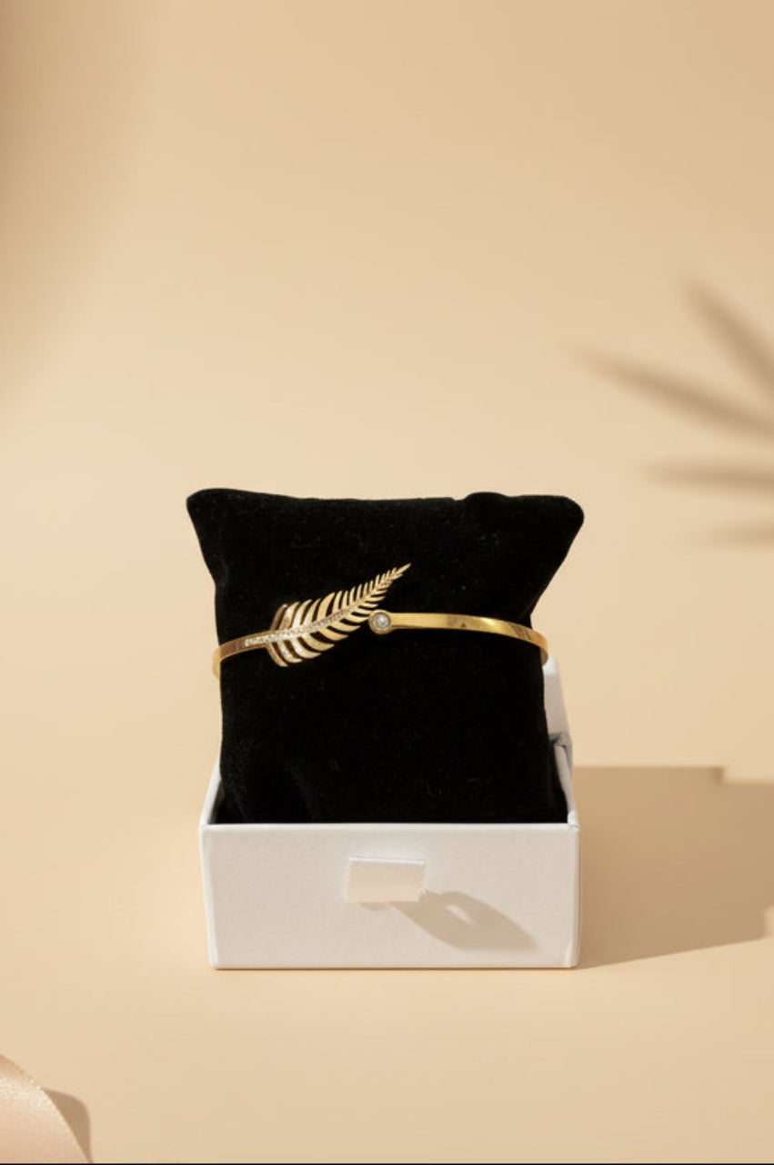 Black jewelry box with a gold bracelet on a beige background