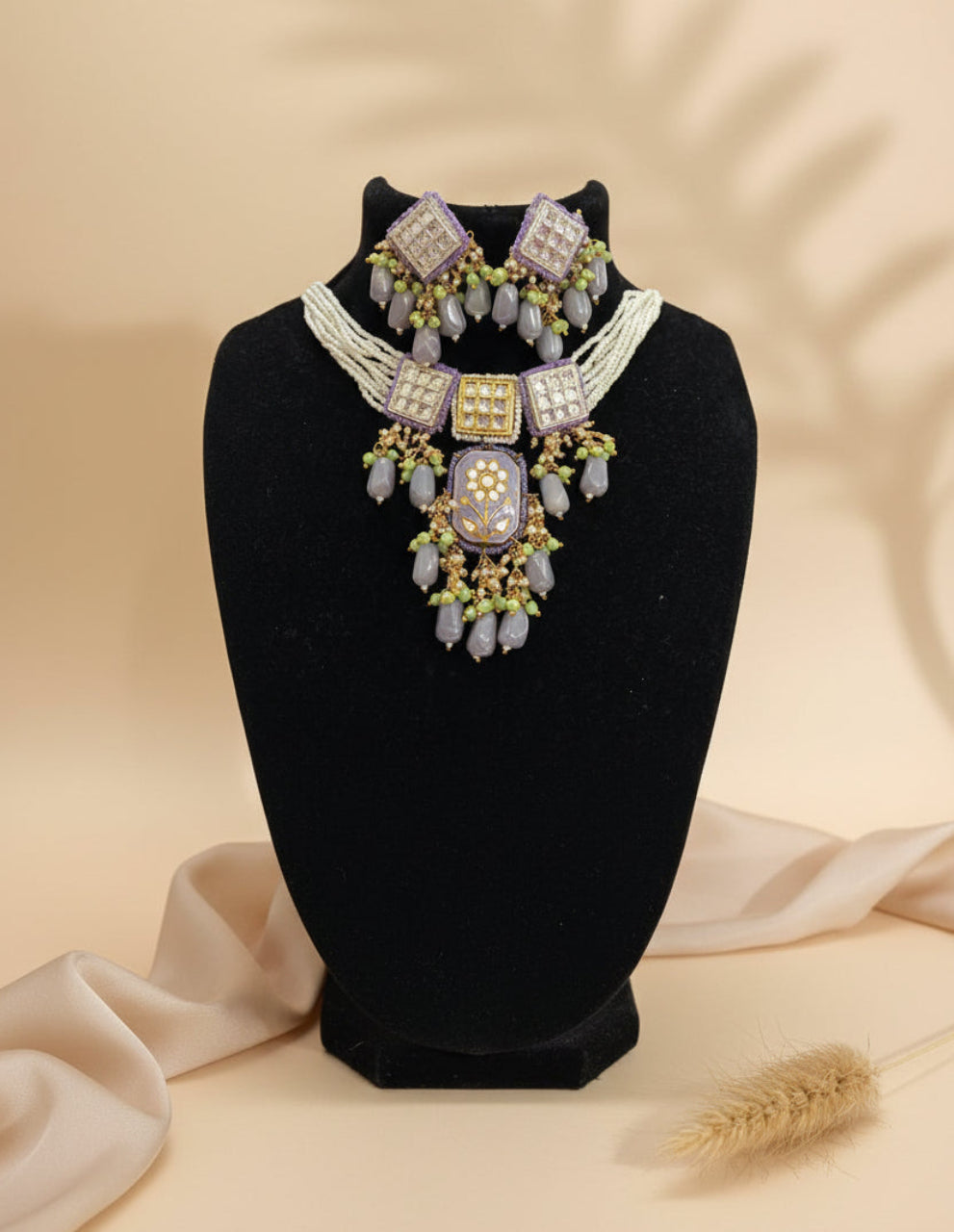 Ornate necklace with purple and green beads on a black stand.