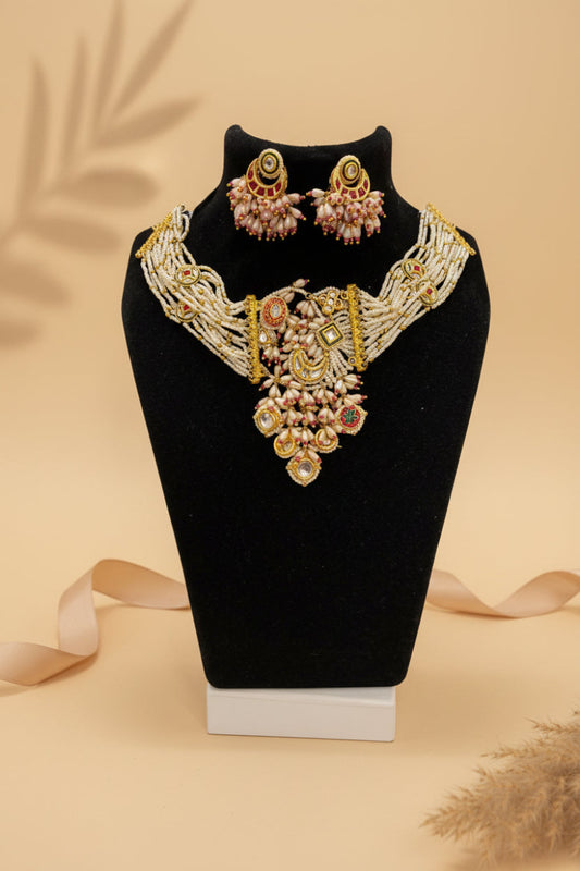 Chicshukra gold-toned Kundan pearl necklace set with matching earrings on a black jewelry display.