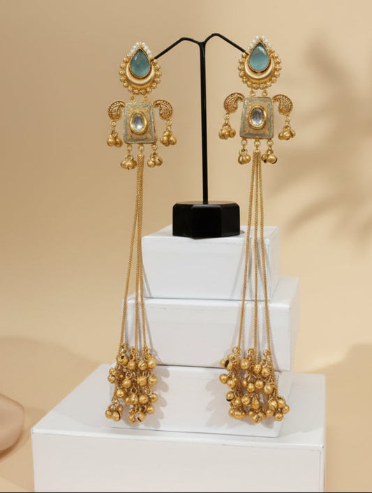 Gold-toned ChicShukra Kashmiri jhumke earrings with teardrop aqua stone, pearl accents, and long ghungroo chain clusters displayed on a stand.