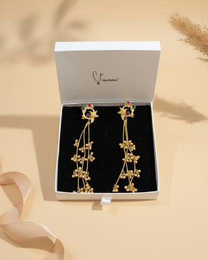 Gold earrings with red stones in a ChicShukra box