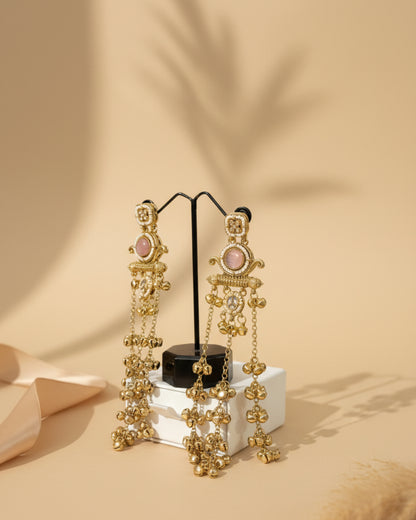Gold earrings with pink stones on a stand against a beige leather background