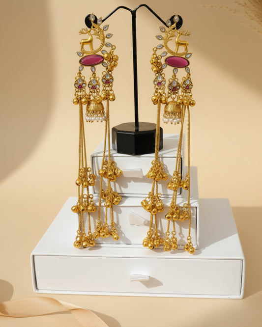 Pair of long gold-plated Kashmiri brass Dehjoor earrings featuring a bird motif, purple teardrop stones, and cascading musical ghungroo tassels.