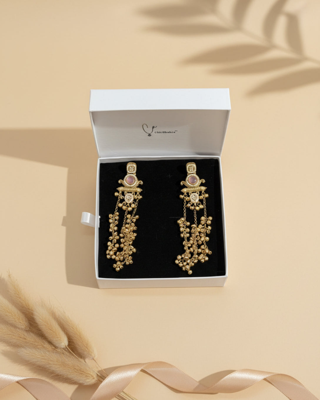 Gold earrings with pink gemstones in a ChicShukra box.