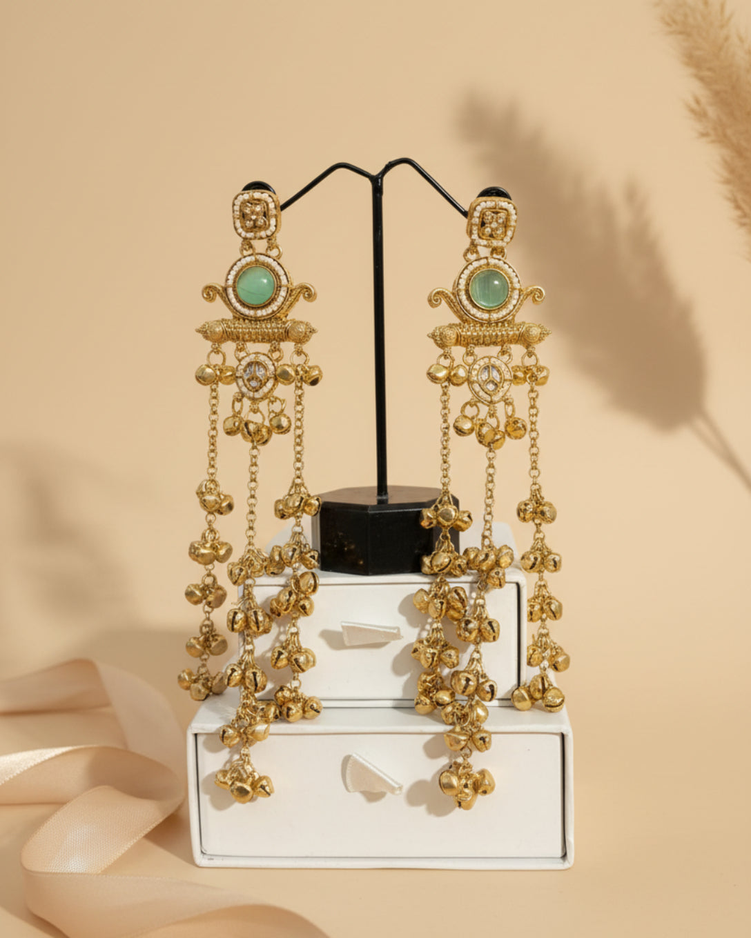 Gold earrings with turquoise stones on a stand against a black leather background