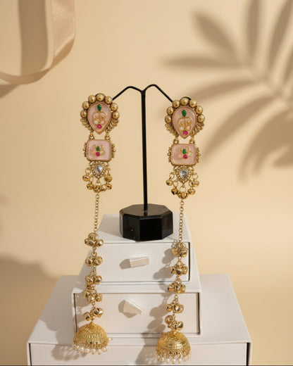 Pair of long gold-plated Kashmiri brass Dehjoor jhumka earrings featuring peach stones, kundan floral motifs, and cascading musical ghungroo tassels.