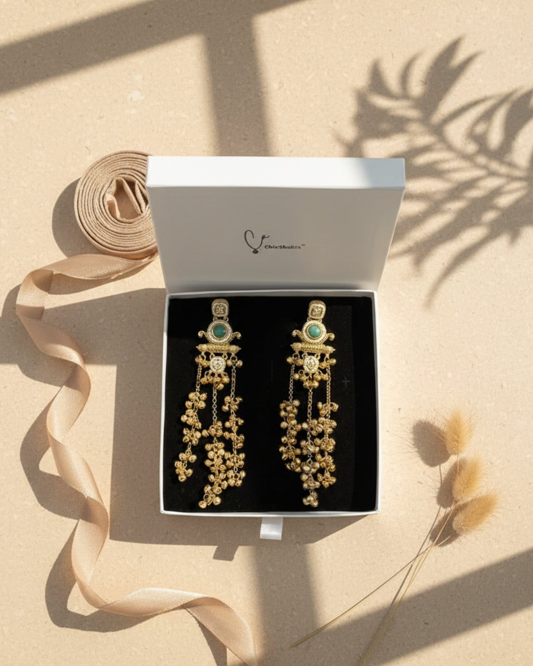 Gold and turquoise earrings in a box with 'ChicShukr' branding.