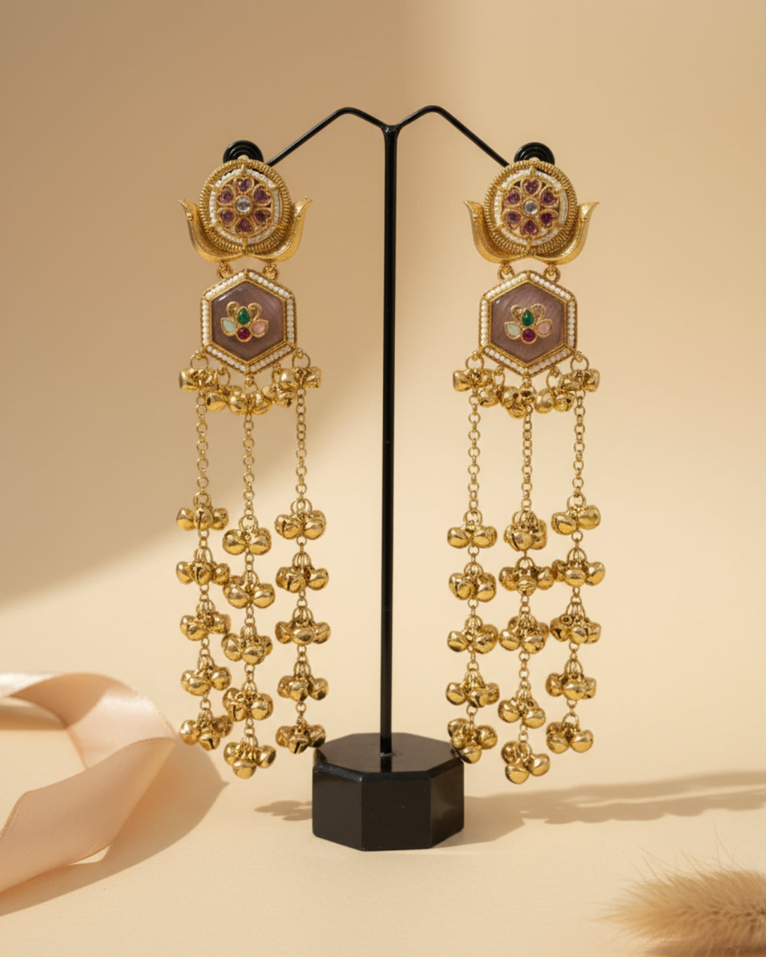 Pair of long gold-plated Kashmiri brass Dehjoor jhumka earrings featuring emerald green teardrop stones and cascading ghungroo bell tassels.