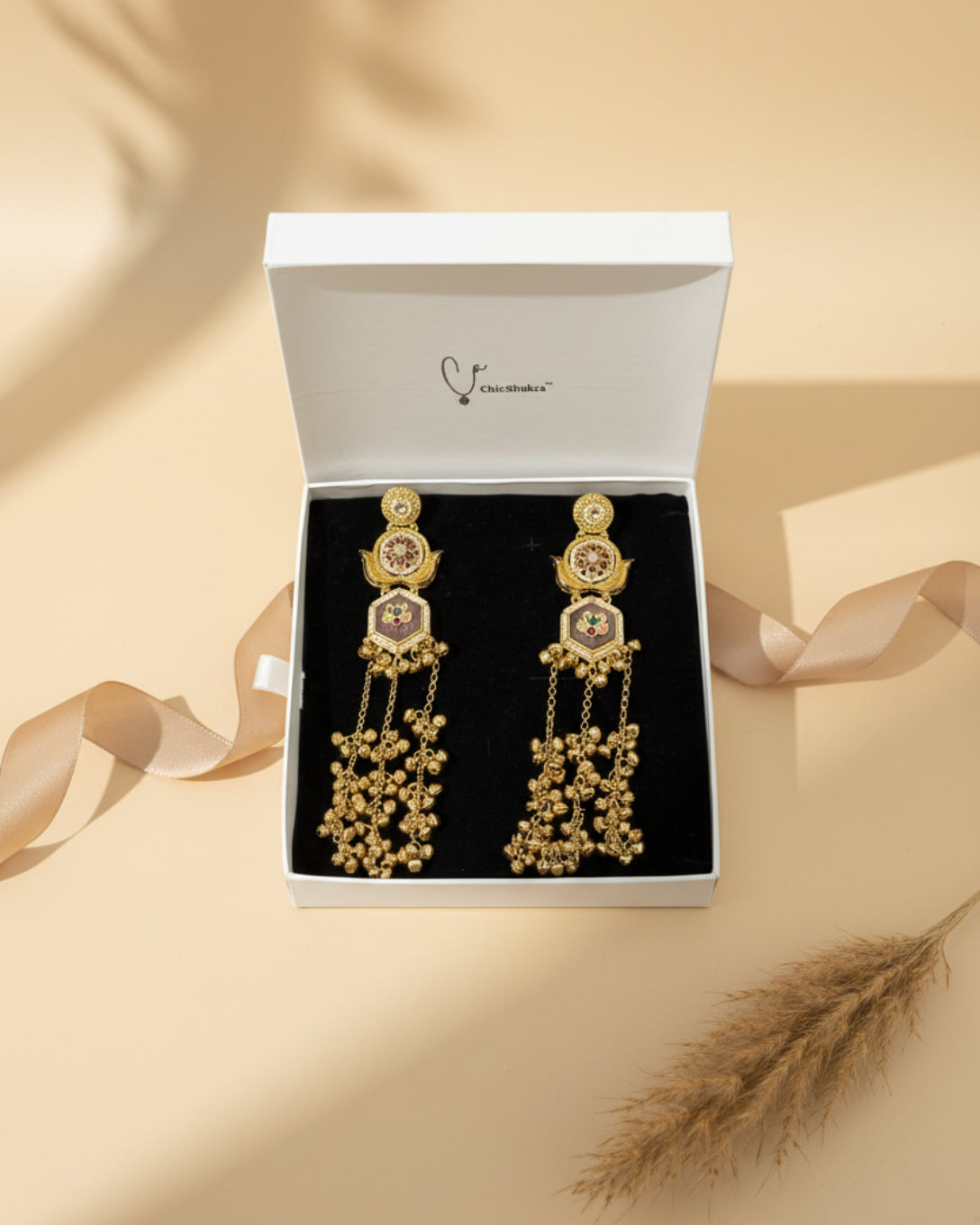 Gold earrings with intricate designs in a ChicShukra box.