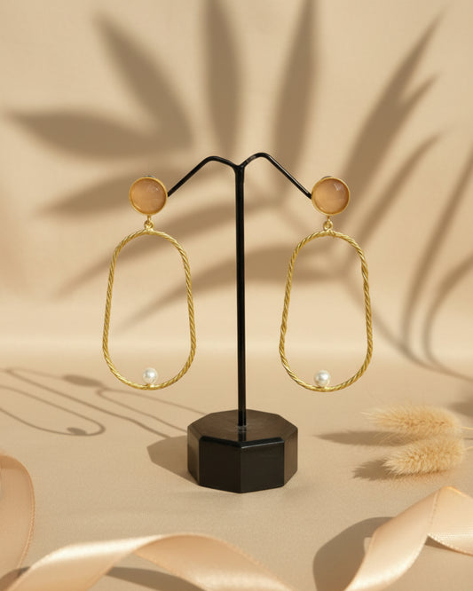 Handcrafted gold-plated brass drop earrings featuring a peach stone stud, a large twisted-texture oval hoop, and a single white pearl accent at the bottom.
