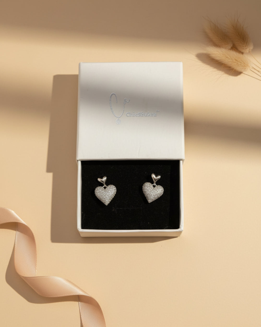 ChicShukra anti-tarnish silver heart-shaped stud earrings featuring a dangling pave heart encrusted with shimmering cubic zirconia stones.