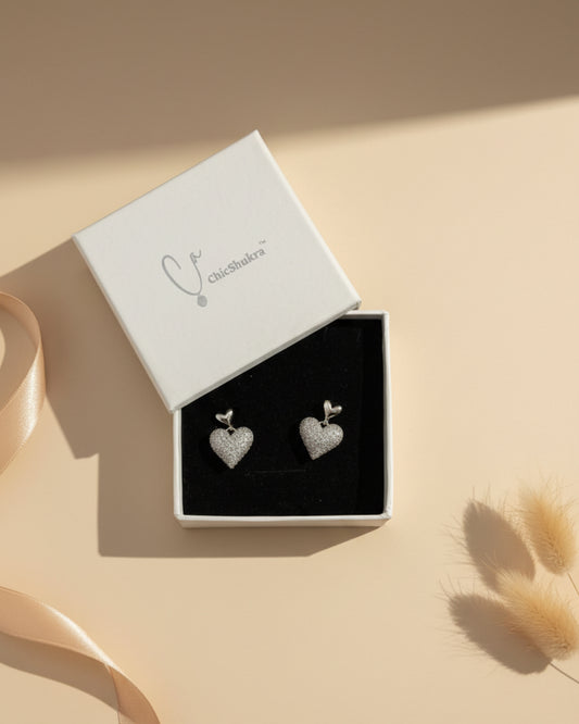 Heart-shaped earrings in a Chic Shukra box on a patterned fabric background