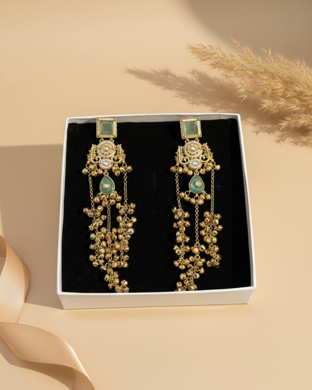 Gold and green earrings in a box with 'ChicShukra' branding.