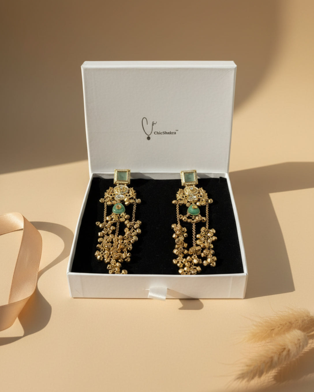 Gold earrings with green stones in a ChieShukra box