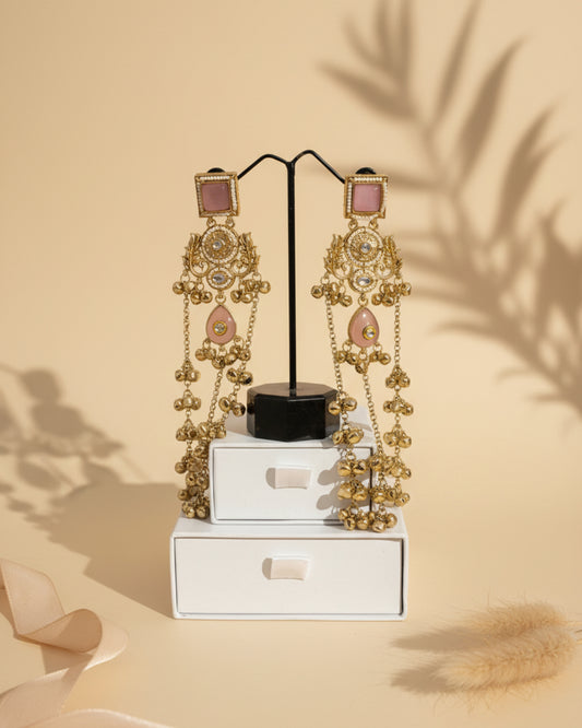 Pair of handcrafted gold-plated Kashmiri brass Dehjoor earrings featuring square pink stone studs, floral filigree, and cascading ghungroo bell tassels.