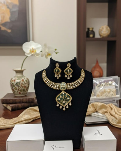 Gold necklace and earrings on a black mannequin bust with a decorative background.