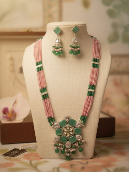 Jewelry set with pink and green necklace and earrings on a mannequin bust.