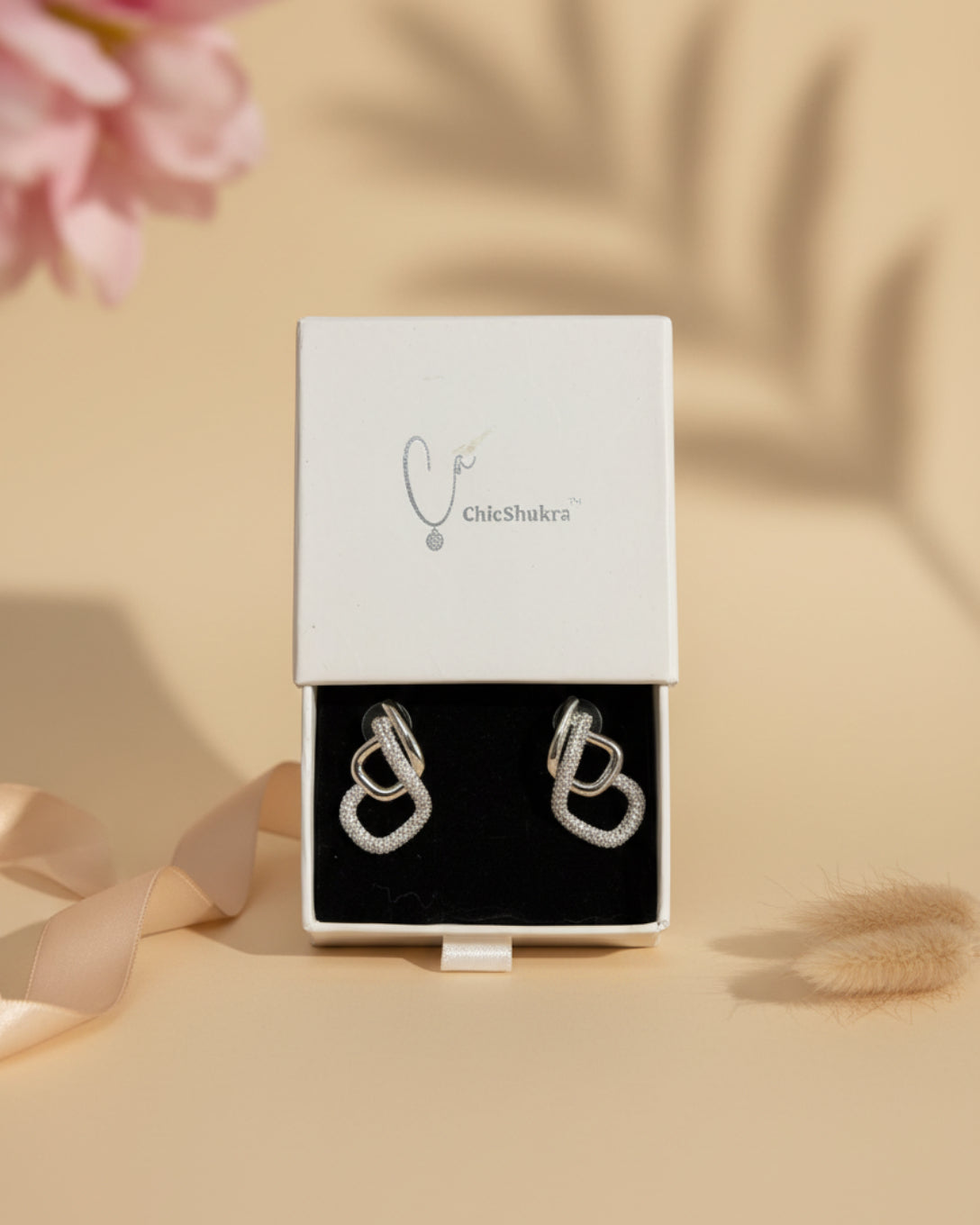 ChicShukra anti-tarnish silver-finish stud earrings featuring an interlocking dual-loop design with shimmering pave-set cubic zirconia stones.